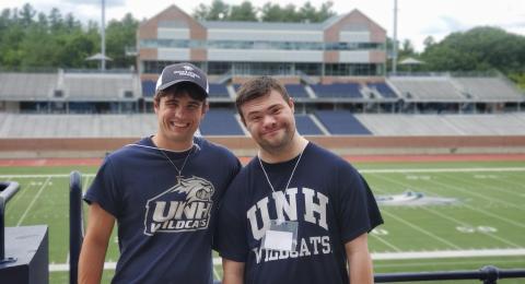 UNH-4U students Garrett and Andrew pose for a photo in front of the UNH football field