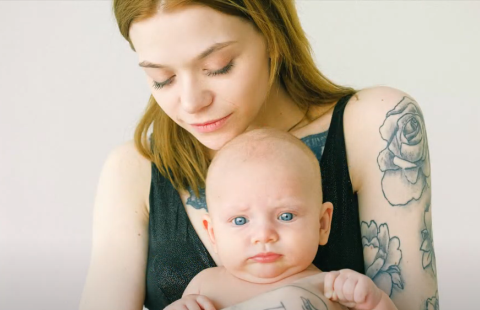 Mother with arm tattoos holding a baby