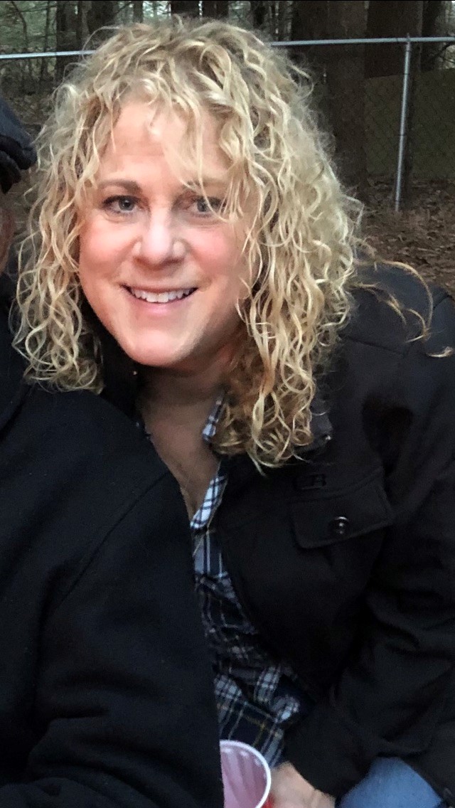 Deb Colanton-Dalzell is a woman with curly blond hair at a farm