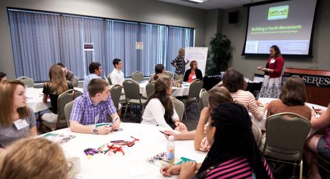 An educator lectures a class of adult learners.