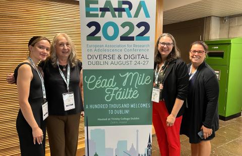 Elizabeth, Nilufer, Heidi, and Adele standing in front of the EARA 2022 display.