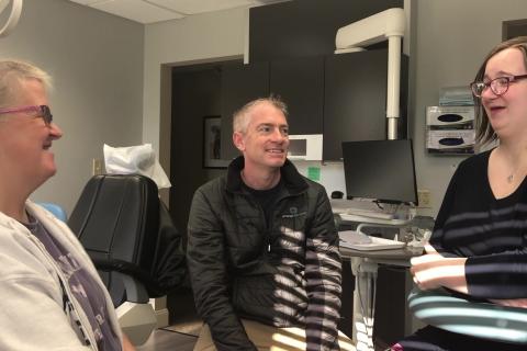 Three people in a dentist's office having a conversation