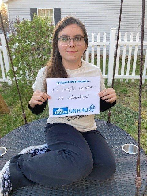 Incoming UNH-4U student Grace holds up an IPSE Day sign that says, "I support IPSE because all people deserve an education!"