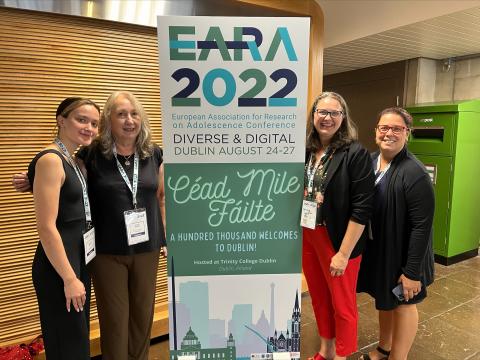 Elizabeth, Nilufer, Heidi, and Adele standing in front of the EARA 2022 display.