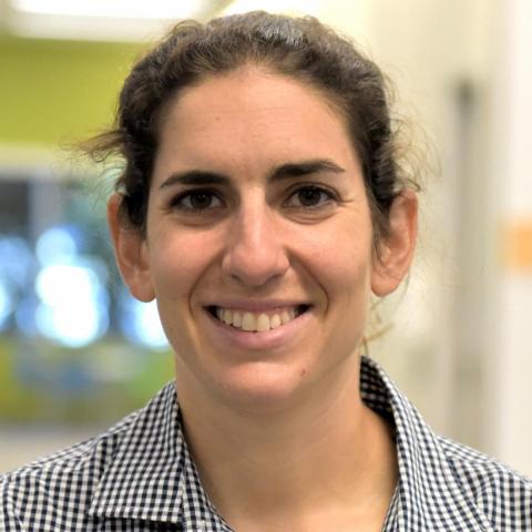 Headshot of Ariel Schwartz, a young woman with brown hair pulled back in a ponytail, wearing a gray button-up shirt.