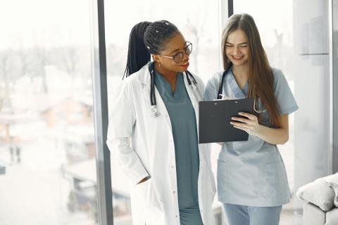 two women healthcare providers look at a clipboard together
