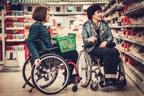 Two women in wheelchairs grocery shopping together