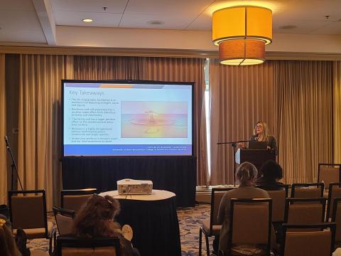 A woman with long blond hair and glasses presents a power point on Key Takeaways to a conference room