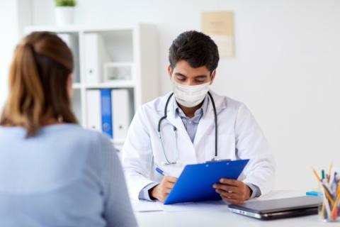 image of a healthcare provider listening and taking notes on a clipboard while a woman talks to them