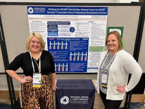 Two women in professional attire standing in front of a poster