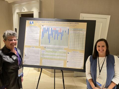 Two women in professional attire presenting a poster