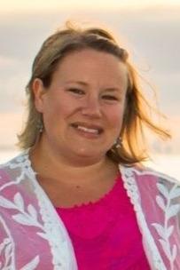 Deanna Scripture is a woman with short blond hair who is pictured outside with the sun setting in the background.