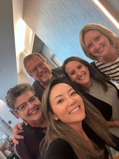 Five people smiling for a group photo at a conference