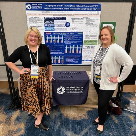 Two women in professional attire at a conference smiling proudly and standing in front of a poster they authored as described in this section.