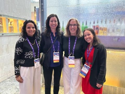 Four women in professional attire standing for a photo at a conference