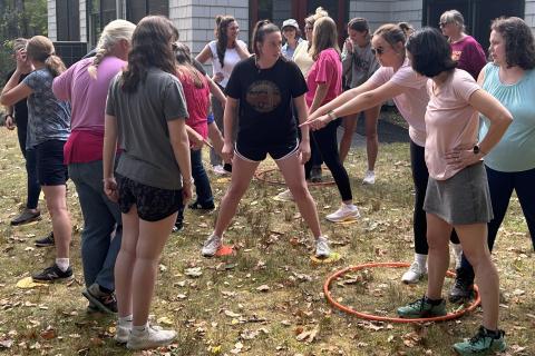 a group of people are doing a team building activity outside involving walking on circles placed on the ground