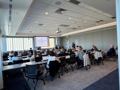 Several people sitting in a conference room watching a presentation