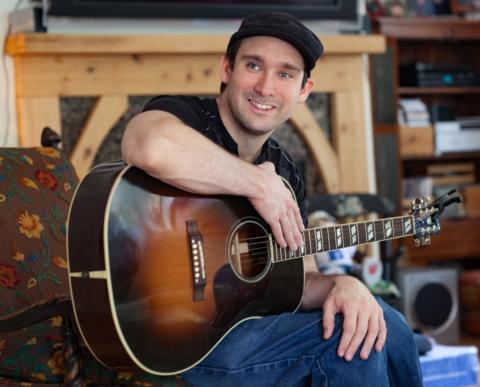 A man smiling with a guitar 