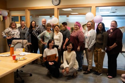 Folks at the Institute on Disability gather together for a group photo in a conference room decked out for a celebration.