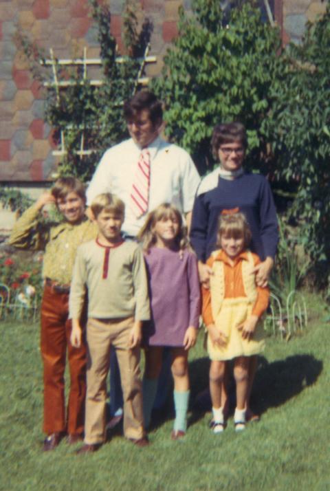 Two parents pose with their four children who look to be between the ages of 6 to 12. They're all wearing nice clothing that dates from the 1970's.