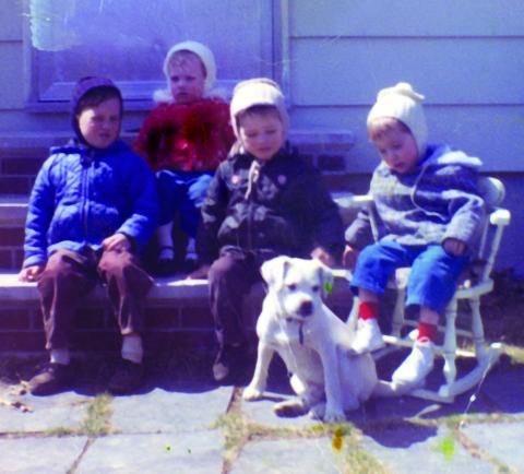 Four young children sit on a stoop with a new family puppy.