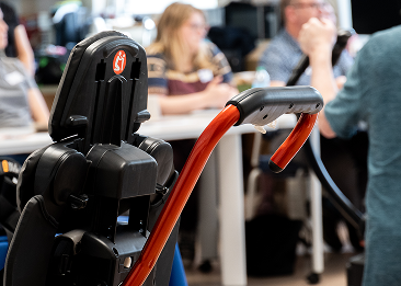 A picture of a wheelchair with a push bar attached behind it.