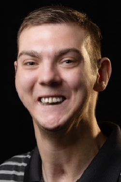 Headshot of Garrett Jones smiling, with short brown hair, wearing a dark striped polo shirt. 