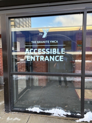 Glass entrance of Granite YMCA Manchester downtown branch with Granite YMCA logo and Accessible entrance signage.