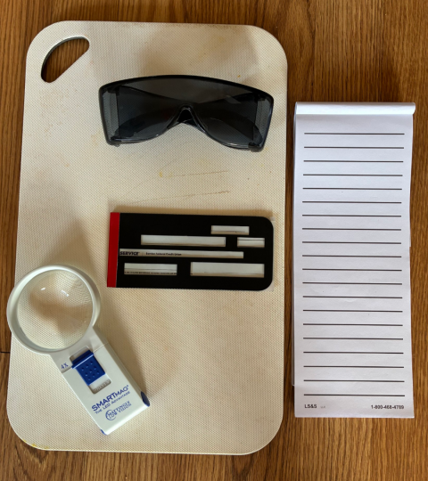 A photo of assistive tools to help with vision loss. There is a pair of classes and two others tools laid out on a table. 