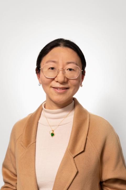 Liu Yang is a woman with pulled back black hair and glasses wearing a professional beige blazer