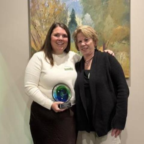 Two women pose with an award.  