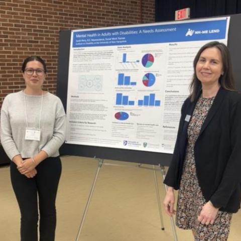 Two women stand by a poster titled "Mental health in adults with disabilities: A needs assessment"